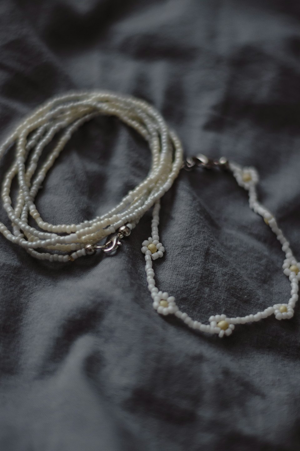 Handcrafted beaded necklace and bracelet resting on grey fabric.